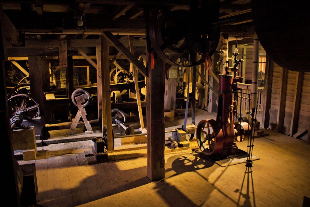 machinery and pulleys sit in the basement of the mill
