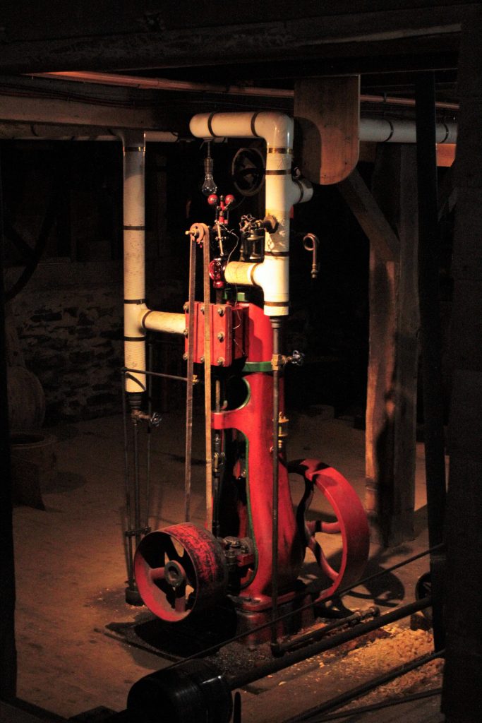 a red vertical engine stands in the basement of the mill